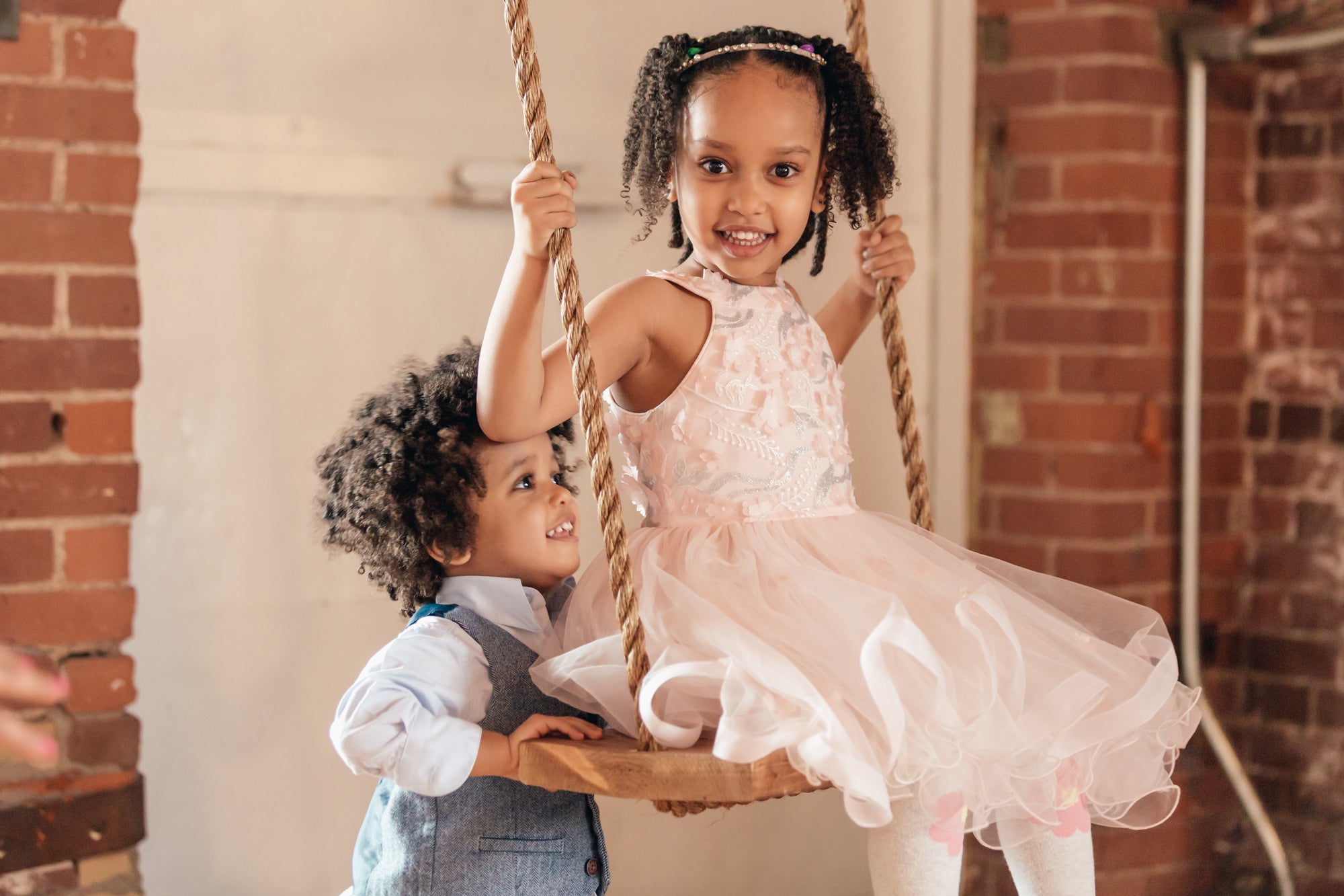 two children playing on an indoor swing